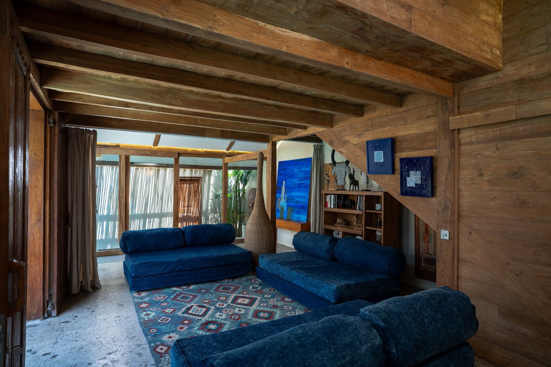 The living room with deep blue sofas and teak beams